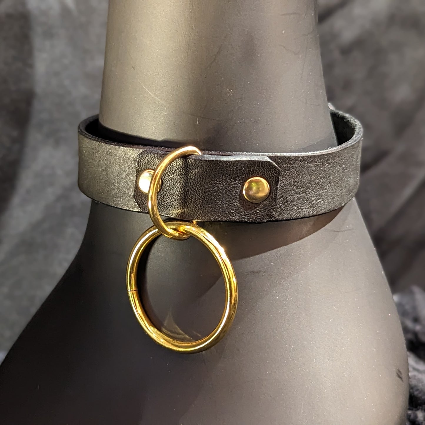 Black leather collar by Smell My Leather. Simple single layer of leather with a 1.5" dangling O-Ring. This has gold hardware.