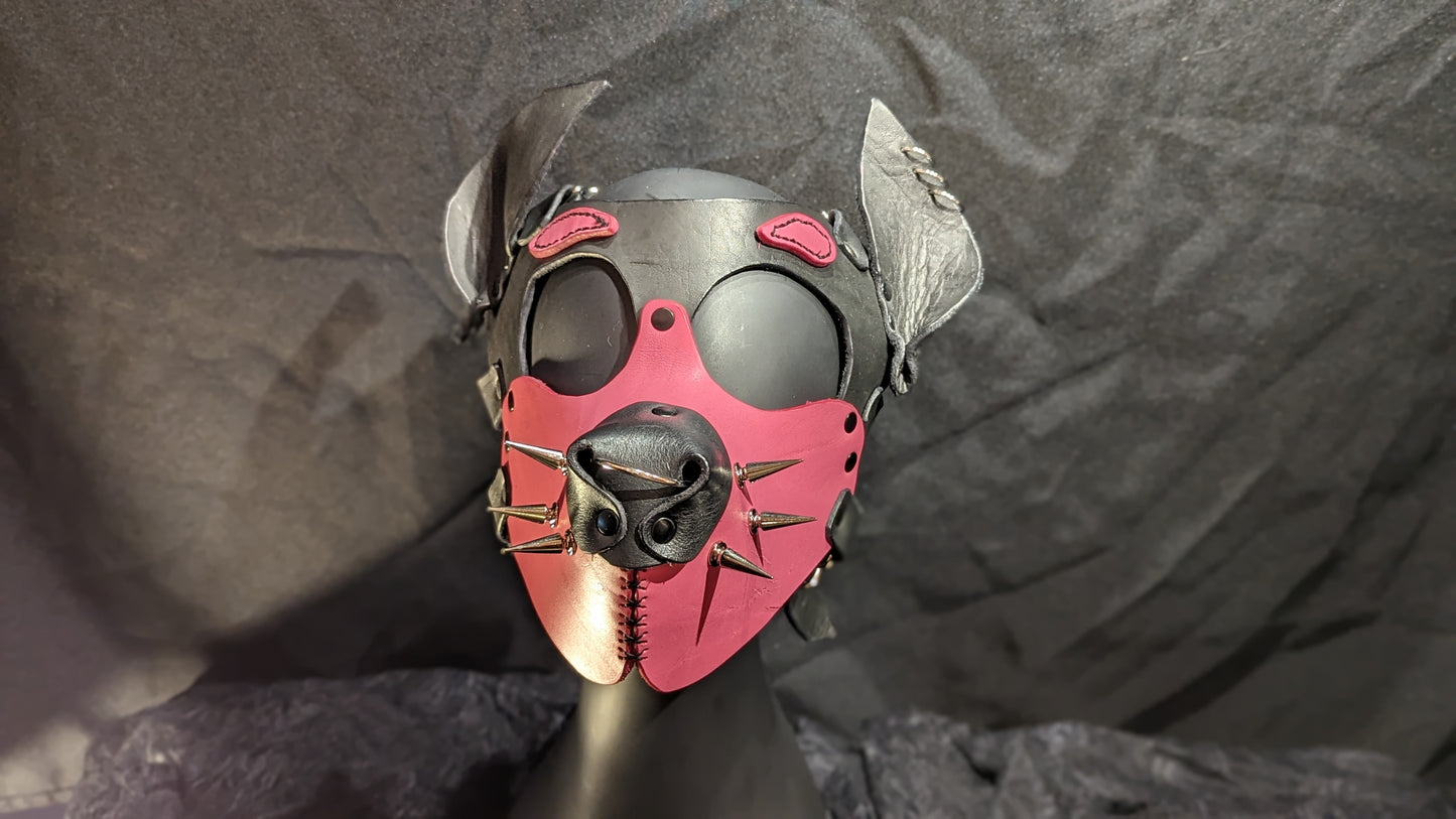 Handmade puphood with a black base color and bright bubblegum pink muzzle and eyebrow and 1 inch silver treecone spike whiskers.. You can see the front face of the hood in this image.