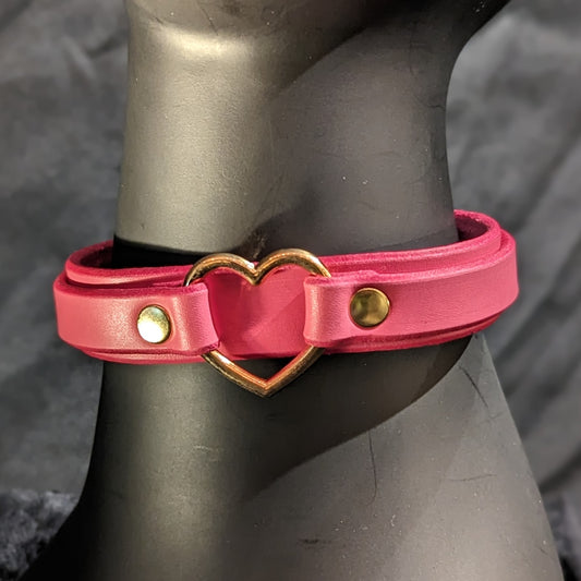 Pink collar with gold heart shaped ring at the center by Smell My Leather. This collar has two layers of leather and gold hardwaree